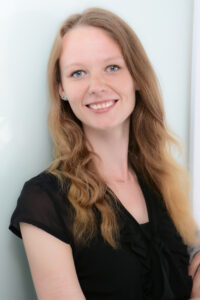 Portrait_Janne_Kleine-Huste Portrait-Bild einer jungen Frau mit langen blonden Haaren, die in die Kamera lächelt.