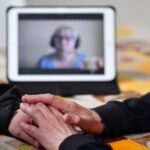 Zu sehen ist eine mögliche Verbindung von Beratungs und Technik mit zwei Menschen im Gespräch im Vordergrund und einer dritten Person im Hintergrund, die per Videokonferenz dazugeschaltet ist.
